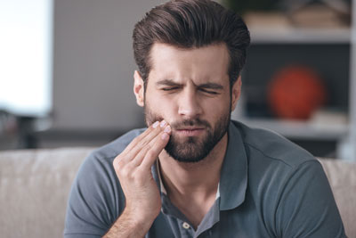 man holding his mouth from tooth pain